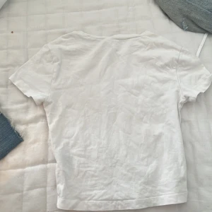 vit t shirt - Säljer en enkel och stilren vit t-shirt i bomull. Perfekt för vardagsbruk eller som basplagg i garderoben. Den har en normal passform och korta ärmar. Passar till alla tillfällen och är lätt att matcha med andra kläder.