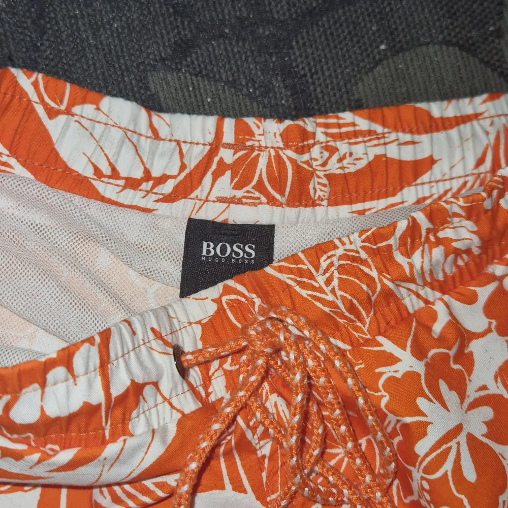 Hugo boss badbyxor med blom motiv nästan helt nya använd 4 gånger som shorts aldrig badat i dom  Köpta för 800kr säljer för 350/400kr pris kan sänkas till 200 250 350 vid snabb affär. Shorts.