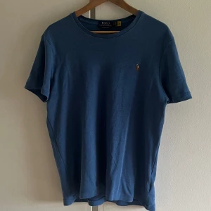 Polo Ralph Lauren T-shirt - Säljer denna skitsnygga Polo tröjan pga att den krympte lite i tvätten, annars väldigt bra skick. Perfekt färg inför sommaren. Storlek L men sitter nu som en M. Hör av dig vid minsta fundering!