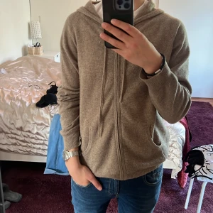 Snygg beige cashmere zip-hoodie i storlek M från Davida Cashmere - Säljer en väldigt fin beige Cashmere hoodie för 1650 kr och är perfekt till sommaren. Nypris 2600 kr. Har använt den 1 elr 2 gånger. Säljer den för att den är lite för för mig. Äkta Cashmere. 9,5/10 skick.