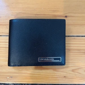 Calvin Klein läder plånbok/korthållare  - En svart plånbok/korthållare från calvin klein i färgen svart. Mycket bra skick då jag bara använt den i en vecka. Original pris 499:-. Pm för mer info eller bilder. Pris kan diskuteras vid snabb affär