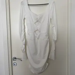 En vit klänning från SHEIN i storlek M. Aldrig använd. Detaljer i ärmarna, utskurna detaljer fram, djup rygg och rynkat tyg baktill.