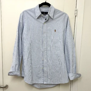 Polo Ralph Lauren Skjorta - Väldigt schysst randig skjorta från Ralph Lauren i storlek M. Använd men fortfarande i mycket bra skick och inga hål/defekter. Pris kan diskuteras vid snabb affär. Skriv vid frågor!