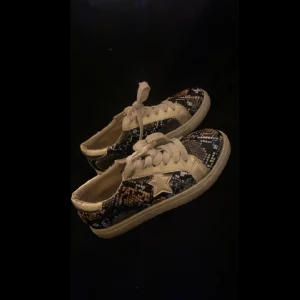 Ormskinnskor med guldig stjärndetalj - Säljer dessa skor med färglatt ormskinnsmönster och guld detaljer bla en stjärna. Perfekta nu till våren!