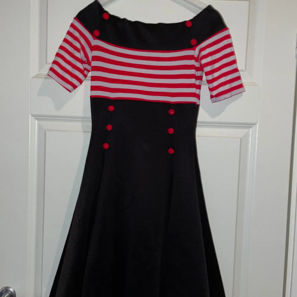 Fin svart och röd offshoulder klänning. Perfekt för att åka raggarbil. Aldrig använd för att det inte funnits ett bra tillfälle. Det är ett skönt elastisk material. Men vet tyvärr inte vart den är köpt då jag fick den i present.. Klänningar.
