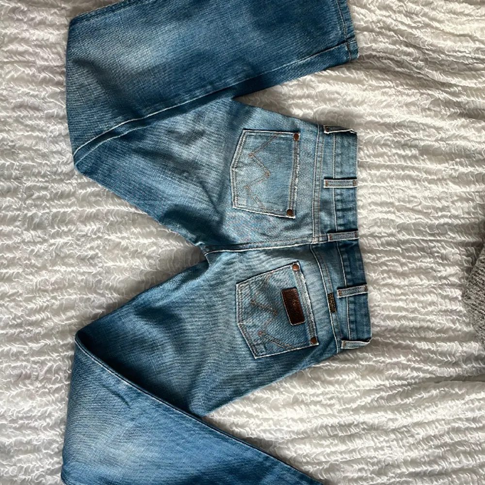Mellanblå lågmidjade jeans från Wrangler. Utsvängda ben. I nyskick. För små för mig som har l26-28 i jeans och är 174.  Midjemått: 38 tvärs över Innerbenslängd: 78. Jeans & Byxor.