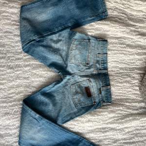 Mellanblå lågmidjade jeans från Wrangler. Utsvängda ben. I nyskick. För små för mig som har l26-28 i jeans och är 174.  Midjemått: 38 tvärs över Innerbenslängd: 78