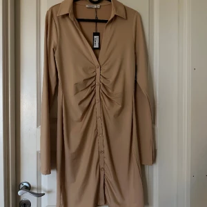 Klänning - En klänning från Nelly som du stänger med knappar framtill, slits i armarna, aldrig använd och prislapp kvar 