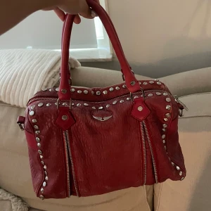 Röd Zadig väska - Röd jättefin väska från Zadig&Voltaire❤️ kommer tyvärr inte till användning längre! Långt band medföljer också!⭐️ Hel och fin men ändå välanvänd! Finns lite tecken på slitage skriv för bild!