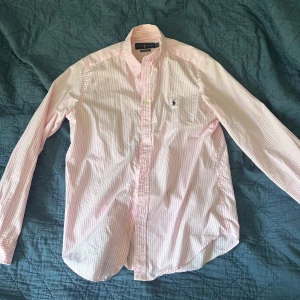 Ralph Lauren Skjorta - Rosa vit randig Ralph Lauren Skjorta i mycket bra skick. Knappt använd. Storlek är 18-20 år. Skulle säga att det passar en S-lite mindre M. 