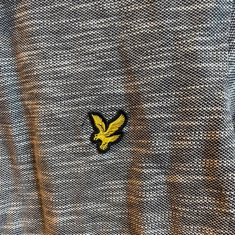 Oanvänd Gråblå pikétröja från Lyle & Scott. Inköpt på Lyle & Scott för ca 1år sedan. Normal i storleken. (Finns en extra knapp med).. T-shirts.