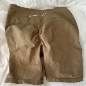 Alphalete - Alphalete amplify shorts brun/beiga storlek M men känns som en S!! Superfint skick ej mycket använda🤎