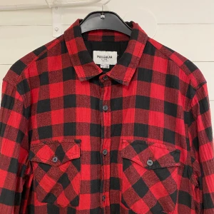 Pull & Bear skjorta - Långärmad rutig skjorta. Storlek L. En knapp saknas vid ena ärmen (se bild) men kan enkelt ersättas av liknande. Frakt tillkommer.