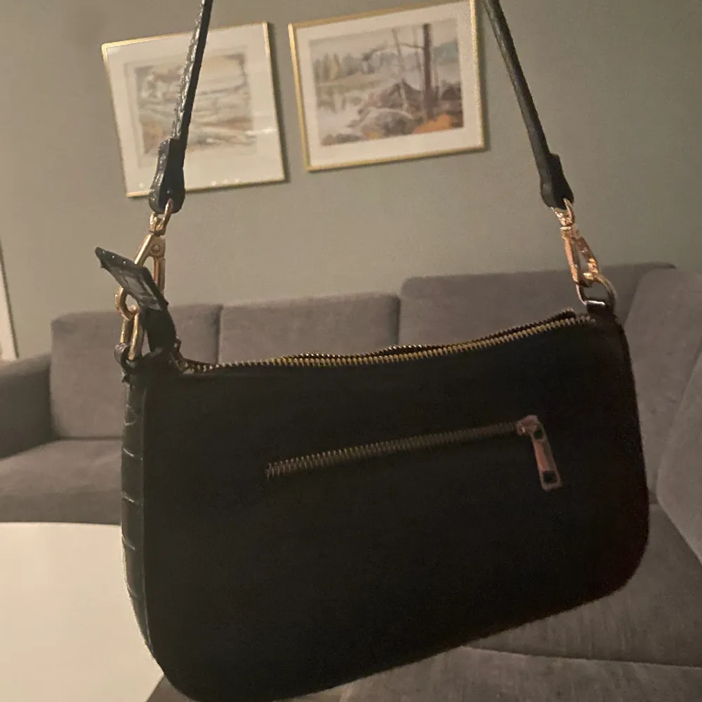 En svart väska som är typ 1 år gammal, knappt andvend. Sitter under armhålan om man har det på axeln. Väskor.