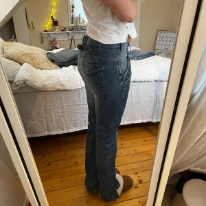 Jeans  - Blåa jeans med super snygg baksida och knäppning! Det är uppklippta där nere. Storlek 40 Midjemått: 41cm Innerben: 77cm