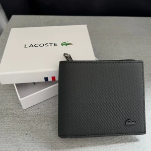 Lacoste plånbok  - Säljer min snygga Lacoste plånbok som är i nyskick (10/10) och endast använd fåtal gånger. Säljer den pga köp av en ny plånbok. Boxen tillkommer.  Hör av dig om du undrar över något🤝