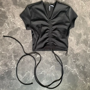 V ringad crop top med knytning - Säljer denna svarta ribbade crop top från HM då den ej används. Är i jättebra skick då den endast använts 1-2 gånger  💸Priset går att diskutera💸