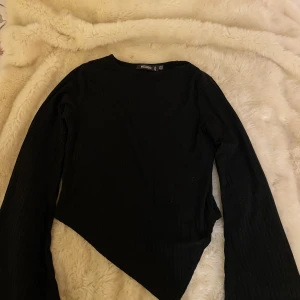 Croppad asymmetrisk topp - Cropppad och ribbad asymmetrisk topp från Missguided med utsvängda ärmar. Använd ett fåtal gånger och är därför i bra skick. Kan även knytas där fram så att den sitter lite tajtare om man vill det. Kontakta mig om du har några frågor💗