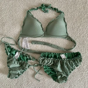 Calzedonia grön / khakigrön glittrig bikini - Bikini från Calzedonia. Endast använd i några timmar på spa. Storlek S i båda trosorna och 75B I bikiniöverdelen. Ordinadiepris cirka 1000kr. Sista bilden är samma modell i annan färg.