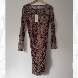 Meshklänning - Meshklänning, genomskinlig, med mönster. Insydd underklänning. Aldrig använd. 