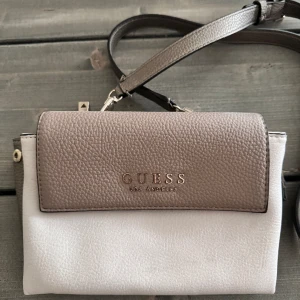 Guess axelremsväska  - En Guess axelremsväska som nästan är helt i nyskick. Köpt för ca 1000kr, hör av dig om du har frågor eller vill se mer bilder