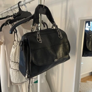 Väska med detaljer - Oanvänd, finns flera fack inuti väskan samt ett längre band till den. 35cm bred och 24cm hög ungefär💕