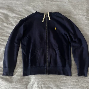 Ralph Lauren Zip Hoodie - Marinblå Zip Hoodie från Ralph Lauren med gul logga  Nypris: 1395kr  Skick: Mycket bra, använd men utan synliga brister 