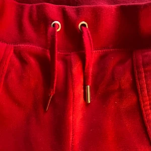 Röd juicy byxor - Säljer dessa juicy byxor i storlek xs. Använda ett fåtal gånger, pluppen på snören har åkt av i tvätten(Man kan få med pluppen) Personen på bilden är 157 cm och är lite långa, skulle passa på folk som är 160+. Står ej för frakt. Pris kan diskuteras.💗