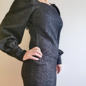 Klänning - Kort klänning med puffärm o rosmönster, går en bit ner på låret. Helt oanvänd,prislapp kvar. 