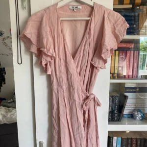 Söt rosa omlottklänning  - Ganska bra skick! Använt relativt mycket så priset är mycket lägre än nypris (850kr) den liknar den oreanga men är inte exakt samma modell, ser såklart mycket finare ut när den är strykt! 