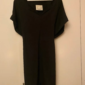 Onesize skjortklänning  - Den är i onesize och kan justeras lätt genom omtaget som knyts antingen fram eller bak. Den går att använda till både byxor eller som den är med strumpbyxor. Har på axlarna en snygg dragkedja. 