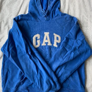 Hoddie från GAP - En fin blå hoddie från GAP! Använd flitigt men är hel! Den har några missfärgningar kring halsen, skriv för fler bilder!