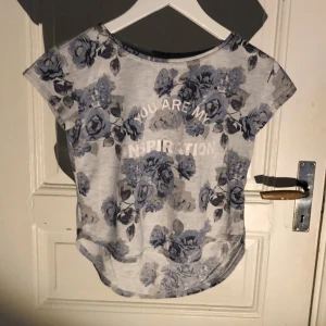 Grå T-shirt med blåa blommor  - En fin blå blommig T-shirt med bra skick 💗