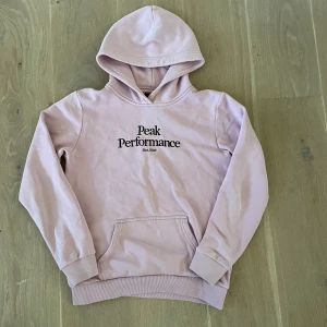 Peak performance hoodie - Rosa hoodie från peak performance i storlek S. Hoodien har ett igensytt hål på baksidan av ärmen men det är inget man märker till. Renaste garderoben därav säljer för 150