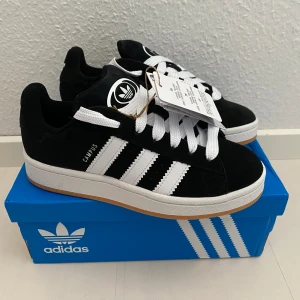 Nya Adidas Campus 00s -storlek 36 (rymliga) - Adidas Originals Campus 00 s j Storlek: 36 Innersulan är 23,5 cm Färg: Svarta (Core Black / Cloud White / Cloud White) Ingår både vita och svarta skosnören.  Nya och oanvända. Ligger kvar i kartong. 