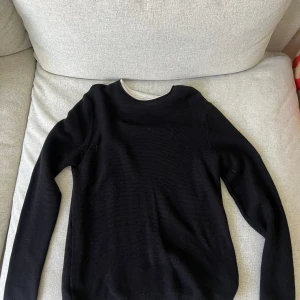 Stickad tröja  - Stickad svart tröja, material med lite ränder i. Den vita kanten är fastsydd. Super skön och bra passform.