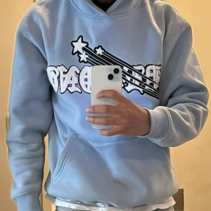 Demond & Hoodie - Denna snygga hoodie från Demond erbjuder både komfort och stil. Den har en ljusblå färg och är dekorerad med en stor, iögonfallande vit och svart grafik på framsidan med texten “Demond” och en stjärnmönsterdetalj. 