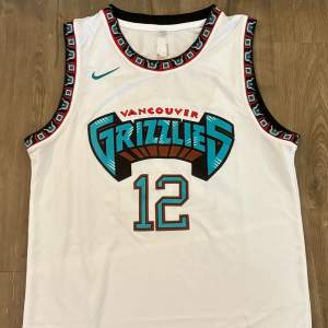 Säljer ett Vancouver Grizzlies basketlinne från Nike i storlek herr M. Linnet är vitt med turkosa och svarta detaljer. Det har nummer 12 på framsidan och baksidan, samt namnet 'Morant' på baksidan. Det är i nyskick och har en cool design med mönstrade kanter.