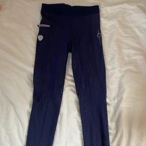 Ridleggings från Covalliero - Säljer ett par mörkblå ridleggings från Covalliero i storlek 164/170. De har en dragkedja på sidan samt två snygga märken på benet. Perfekta för ridning och väldigt bekväma att ha på sig.