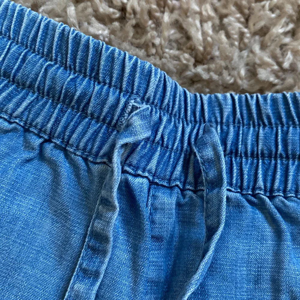 Säljer ett par snygga blå jeansshorts från &Denim i storlek XS. De har en elastisk midja med knytband och två fickor både fram och bak. Perfekta för sommaren och riktigt bekväma att ha på sig. Passar både till vardags och till stranden!. Shorts.