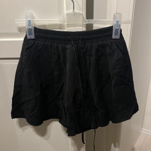 Svarta shorts från BikBok - Ett par svarta shorts från BikBok i storlek XS. Shortsen har en elastisk midja och är tillverkade i ett lätt och bekvämt material. Ser ut som en kjol på!!