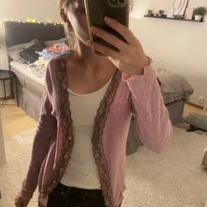 Rosa kofta från Kookai - Säljer en superfin rosa kofta från Kookai. Den är i storlek S och har långa ärmar. Koftan är dekorerad med spetsdetaljer längs kanterna som ger den en söt och romantisk look. Perfekt för både vår och höst! 💖