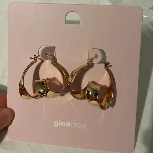 Nya örhängen från Gina  - Ett par oanvända Gabriella örhängen i guld från Gina Tricot. Örhängena har en elegant och modern design med en vriden form. Originalförpackning. Originalpris 99kr. Säljer även fler smycken som ni kan få för ett paketpris.