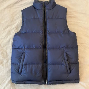 Ralph Lauren down väst, XS - Mörkblå Ralph lauren väst i storlek XS, är använd ett par gånger men är fortfarande i bra skick, denna väst går även att vända ut och in på så att man kan använda andra sidan på västen om man vill göra det  
