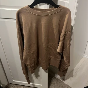 Brun sweatshirt  - Brun sweatshirt med bokstaven D i orange färg. Storlek S från Bik Bok 