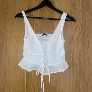 Vit topp - Jättefin och somrig vit topp fröna ginatricot. Den har resår i ryggen och knytning där fram. Helt oanvänd då jag inte fått användning av den bara. Storlek xs. Köparen står för frakten.