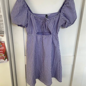 Lila rutig klänning  - Lila rutig klänning som är ganska kort med utklippnad under brösten.  Pris exklusive frakt