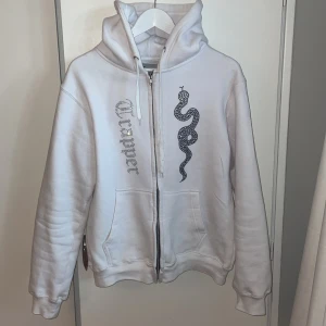 rhinestone hoodie - Tja! säljer min rhinestone zip hoodie av märket Madebytrappers. Den är storlek L och av de jag ser så sitter alla rhinestones kvar. enda negativa är att ena snöret har remsat upp litegrann (se bild). kom dm för mer info och bilder