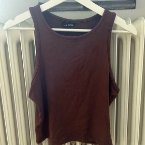 Brun ribbad linnetopp från Weekday - En brun ribbad linnetopp från shein. Toppen har en rund halsringning och är ärmlös, vilket gör den perfekt för varmare väder.