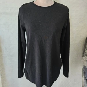 Svart långärmad tröja från ASOS DESIGN - En svart långärmad tröja från ASOS DESIGN MATERNITY. Tröjan är designad för mammakläder och har en enkel, stilren design med rynkade detaljer på sidorna för extra komfort och passform.